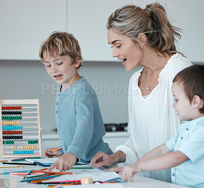 Buy stock photo Caucasian mother helping son with homework. Proud mom looking at childs drawings learning about colours. Young mother at home with two sons. Kids using colouring pencils. Teacher tutor with little students