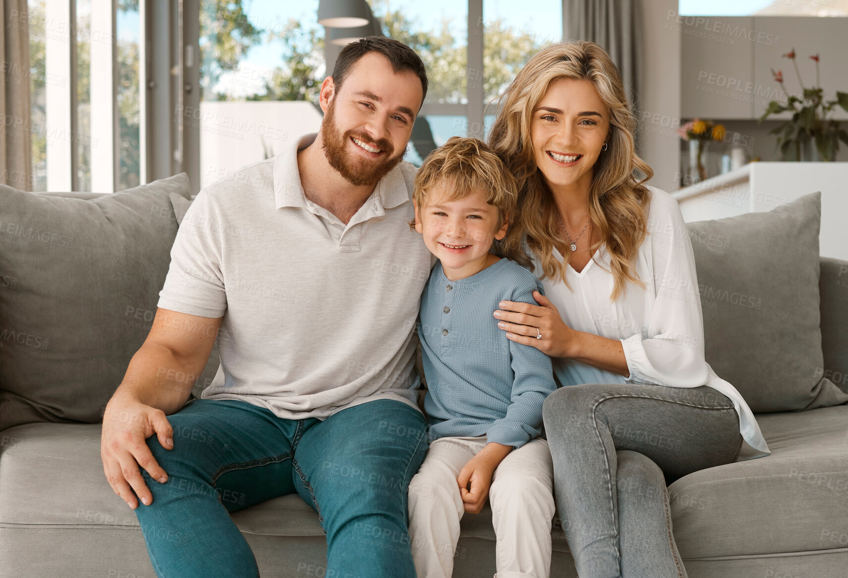 Buy stock photo Happy caucasian family of three looking relaxed while sitting and bonding on the sofa together. Adorable little blonde boy chilling on a couch with his loving parents while hugging them