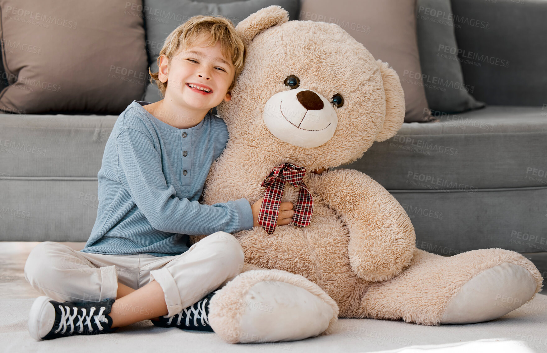 Buy stock photo Portrait of one happy little caucasian boy smiling while hugging a big and cosy fluffy teddy bear on the floor in the lounge at home. Adorable kid relaxing and playing with soft stuffed toy alone