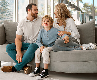 Happy caucasian family of three looking relaxed while sitting and bonding on the sofa together. Adorable little blonde boy chilling on a couch with his loving parents while chilling with them