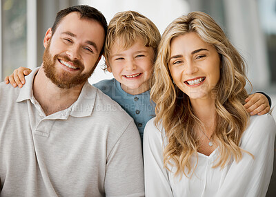 Buy stock photo Portrait of happy parents and their little son at home. Adorable caucasian boy smiling with an arm around his mother and father. Young parents enjoying free time with their son on weekend