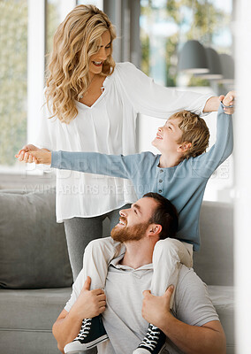 Buy stock photo Happy caucasian family bonding at home. Excited little boy sitting on his father's shoulders and holding his mother's hands while pretending to fly for play and fun. Loving parents relaxing with son