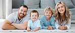 Portrait of smiling caucasian family of four lying and relaxing on the floor at home. Carefree loving parents bonding with cute little sons. Playful young boys spending quality time with mom and dad