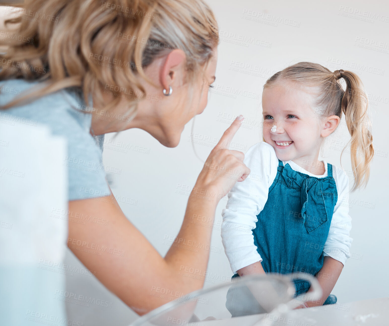 Buy stock photo Little girl putting flour on her mothers nose. Little child baking with her mom. Mother and daughter bonding while baking in the kitchen. Parent baking with her kid.