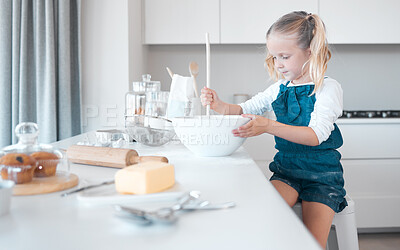 Little girl mixing a bowl of batter. Young child baking alone in the kitchen. Little girl sitting at her kitchen counter. Caucasian girl holding a mixing bowl. Young child baking at home.