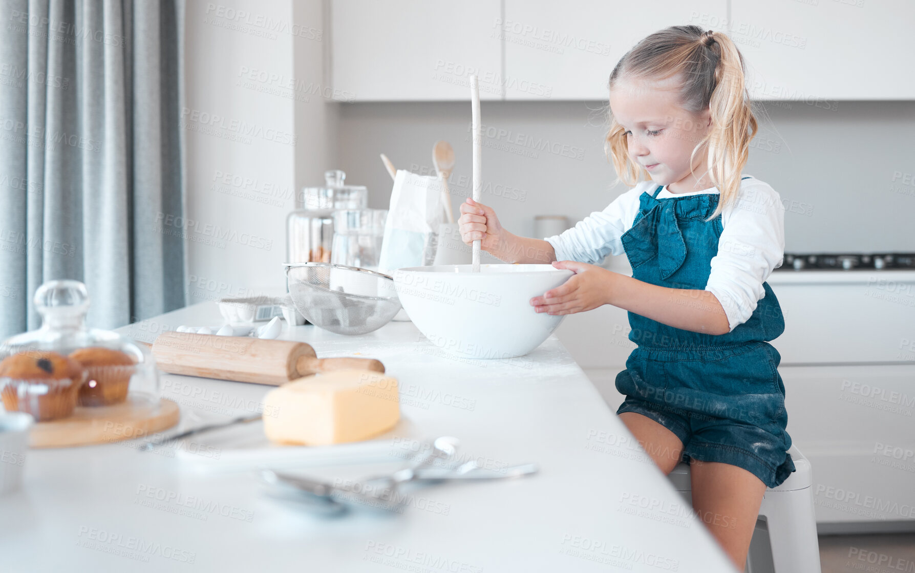 Buy stock photo Little girl mixing a bowl of batter. Young child baking alone in the kitchen. Little girl sitting at her kitchen counter. Caucasian girl holding a mixing bowl. Young child baking at home.