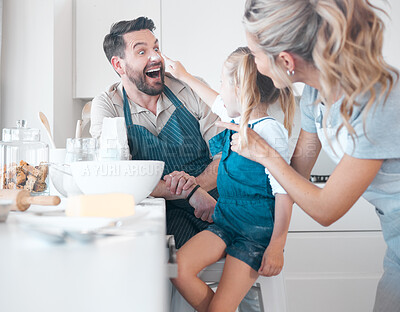 Buy stock photo Playful caucasian family baking together. Little girl putting flour on her fathers nose. Cheerful young family enjoying cooking together. Little child playing and baking with her parents.