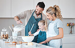 Father pouring a jug of milk into batter. Happy father baking with his daughter. Caucasian family baking together.Smiling parents helping their child bake. Little girl mixing a bowl of batter.