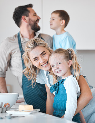 Buy stock photo Mother and father baking with their children. Siblings baking with their parents in the kitchen. Portrait of a mother bonding with her daughter. Happy woman hugging her child. Family baking together