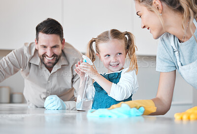 Buy stock photo Happy family cleaning the kitchen together. Little girl spraying disinfectant from a bottle. Caucasian family cleaning the kitchen counter together. Mother and father bonding with their daughter