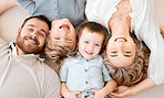 Portrait of smiling caucasian family of four from above lying and relaxing on floor at home. Faces of carefree loving parents bonding with sons. Young boys spending quality time with mom and dad