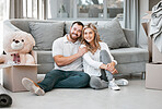 Young happy caucasian couple hugging sitting on the floor of their new house in the lounge. Husband smiling and giving his wife a hug after moving into a new apartment