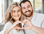 Portrait of newlywed caucasian couple making heart shape with hands and holding house keys to move into new apartment. Relocating after buying first home and securing loan for property or real estate