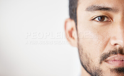 Buy stock photo Close up of mixed race male looking serious against a grey background. Asian male standing indoors with no expression and copyspace