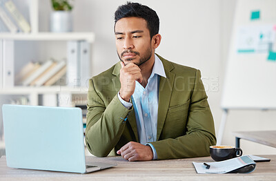 Buy stock photo Young focused mixed race businessman working alone on a laptop in an office at work. One hispanic male boss thinking while reading an email on a laptop. Man sitting at a desk looking at a laptop