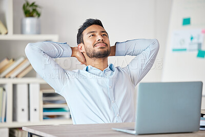 Buy stock photo Young mixed race businessman resting with his arms behind his back working on a laptop in an office at work. Hispanic man relaxing while thinking. Male boss enjoying success alone at work