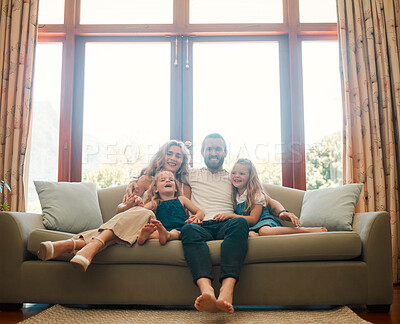 Buy stock photo Young happy content caucasian family holding a cardboard as a roof covering them sitting on the floor at home. Cheerful little girls bonding with their mother and father. Loving parents spending time with their cute daughters