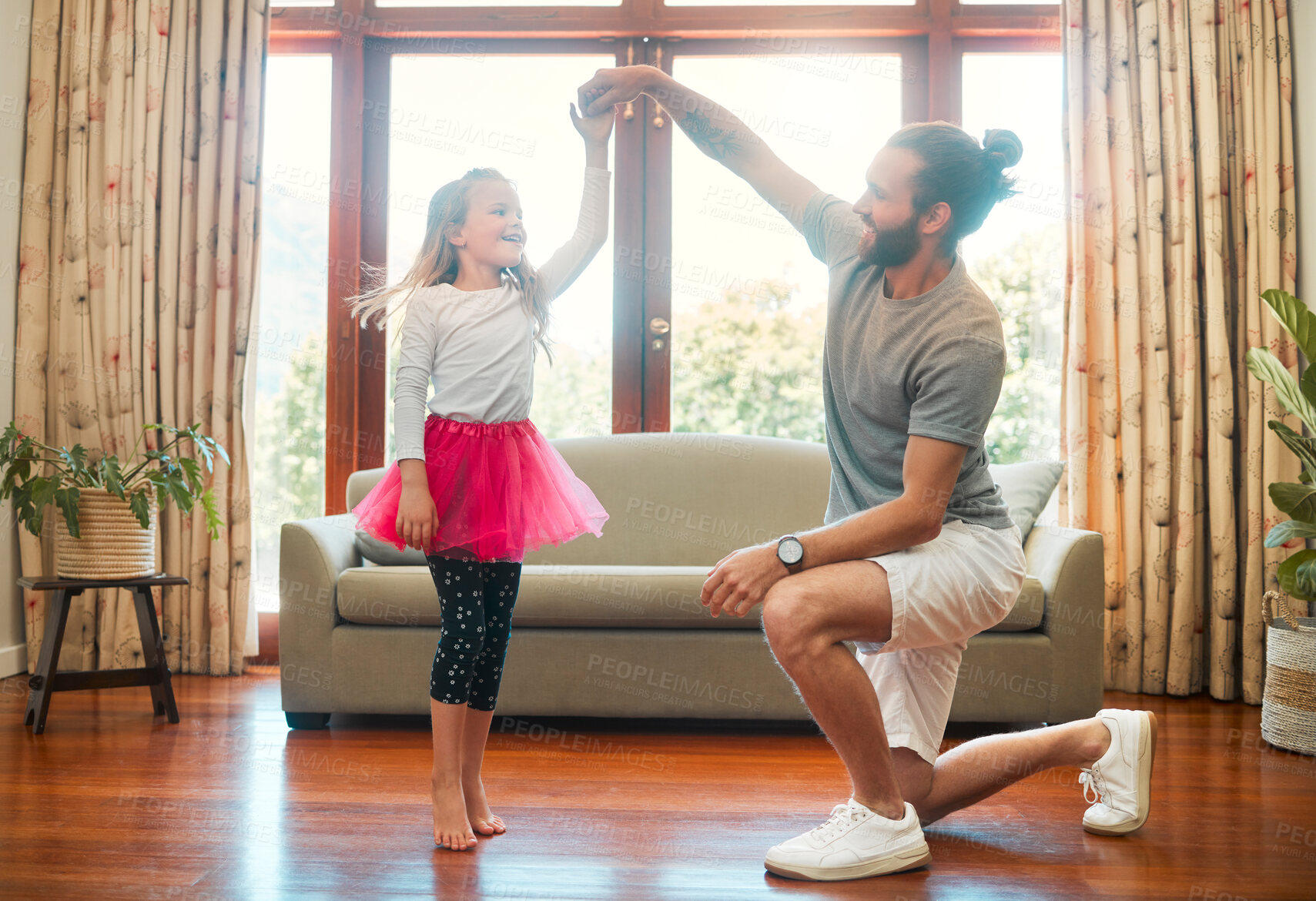 Buy stock photo Young happy caucasian father and daughter dancing together in the lounge at home. Cute cheerful little girl practicing a dance with her dad. Father helping a child with a dance