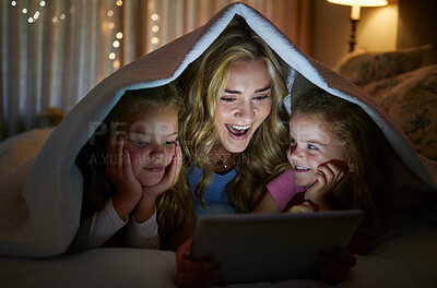 Buy stock photo Young happy caucasian mother using a digital tablet with her little daughters before bedtime at home. Cute comfy siblings watching a movie on a digital tablet with their mom