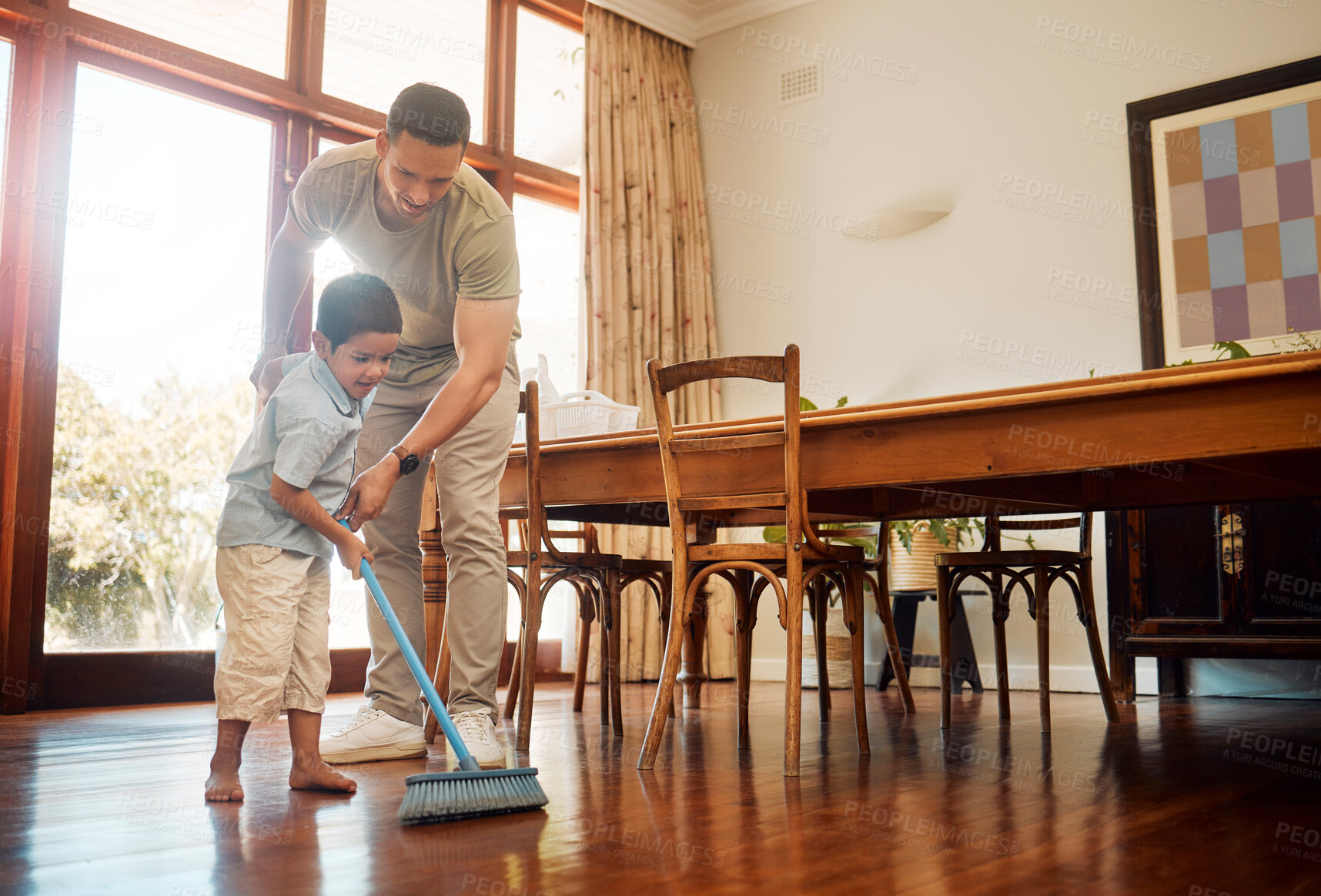 Buy stock photo Mixed race father helping little boy sweep dust and dirt on wooden floor with broom for household chores at home. Cute boy helping dad with daily spring cleaning tasks. Kid learning to be responsible