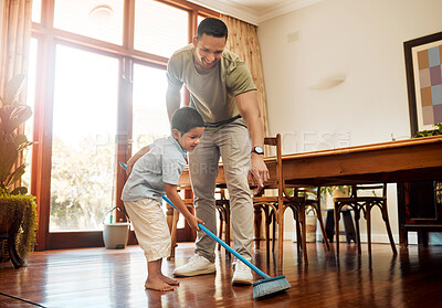 Father pointing to show dust and dirt on wooden floor for son to sweep with broom for household chores at home. Cute boy helping dad with daily spring cleaning tasks. Kid learning to be responsible