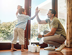 Young happy mixed race father and son giving each other a high five while cleaning at home. Little hispanic boy helping his dad wash windows. Parent and child joining hands to celebrate achievement