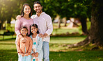Portrait of happy asian family relaxing and sharing quality time on a sunny day in nature in a park or garden with copyspace. Loving parents bonding and having fun with carefree smiling daughters