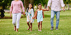 Two adorable little girls walking outside in park with parents. Sibling sisters out for a walk outdoors with parents on a sunny day. Enjoying nature and family