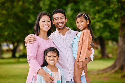 Buy stock photo Portrait of happy asian family standing close together in a park. Adorable little girls enjoying free time with their mother and father on a weekend outside. Smiling couple embracing their daughters