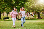 Mixed race family in the park. Happy young mother and father piggybacking their son and daughter outside. Couple carrying their kids while walking on grass during. Two sisters on parents' backs