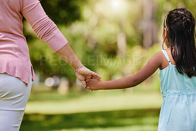 Buy stock photo Rear view of mother holding her daughter's hand in a park. Mixed race single parent enjoying free time with child outside. Little hispanic girl trusting and bonding with her single mother on a weekend