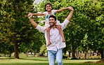 Happy asian single father carrying daughter on his shoulders in the park. Smiling man and child pretending they can fly with their arms outstretched. Single parent bonding with his little girl outside