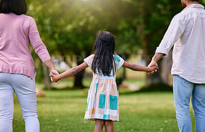 Buy stock photo Rear view of parents and little girl holding hands while walking outdoors in park on a sunny day. Loving and caring family with one child bonding and having fun outdoors