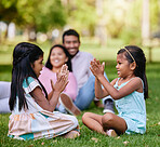 A happy asian couple lying together on grass outside, loving parents enjoy quality time with their little daughters playing a game. Couple bonding during family time at park with adopted foster sister