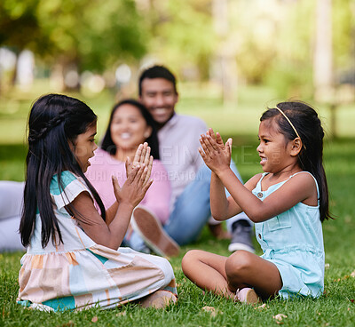 Buy stock photo A happy asian couple lying together on grass outside, loving parents enjoy quality time with their little daughters playing a game. Couple bonding during family time at park with adopted foster sister