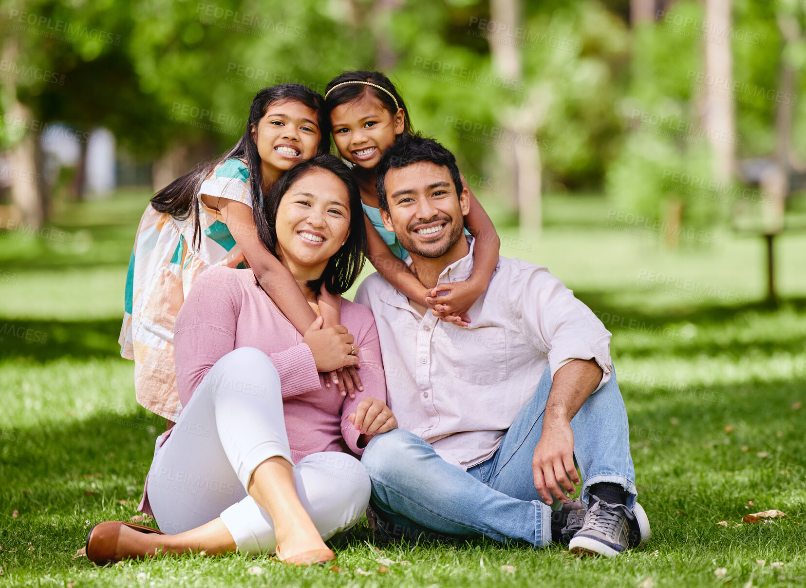 Buy stock photo Hug, portrait and asian family at a park smile, happy and having fun outdoor together. Face, love and children with parents on forest ground, sitting and embrace while enjoying nature on the weekend