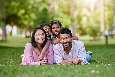 Buy stock photo Portrait of happy asian family lying on grass in a park. Adorable little girls spending time with mom and dad on a weekend outside. Smiling couple lying on lawn with their daughters on their back