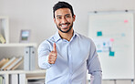 Young happy handsome mixed race businessman showing a thumbs up standing in an office alone at work. One pleased hispanic male boss smiling expressing support and agreement with a thumb up 