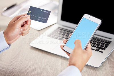 Closeup of an unknown businessman using a laptop, smartphone and credit card at work. Male purchasing items online using his wireless mobile device and credit card while sitting at his desk at a office