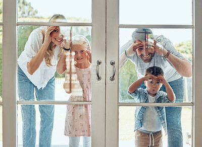 Curious couple with little kids standing and peering into their new home. Excited smiling caucasian family looking at and checking their house from the door. Adorable boy and girl with their parents