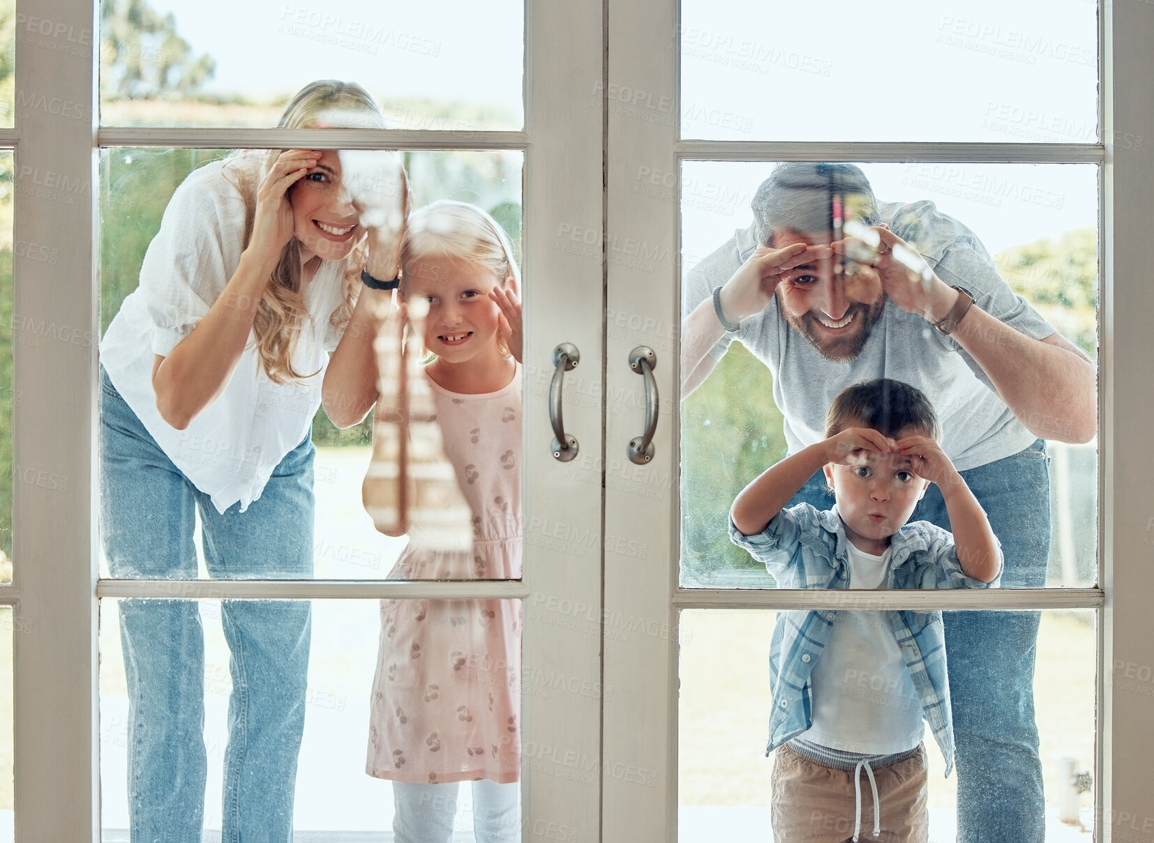 Buy stock photo Curious couple with little kids standing and peering into their new home. Excited smiling caucasian family looking at and checking their house from the door. Adorable boy and girl with their parents