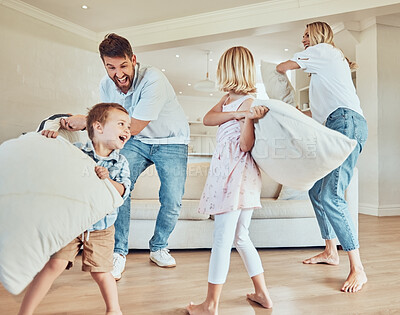 Playful parents with little kids pillow fighting in their living room. Adorable caucasian children enjoying free time with their mother and father. Happy family standing and play fighting at home