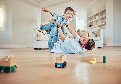 Father lifting his son. Dad lying on the floor lifting his child. Little boy flying in dads arms. Excited father playing with his kid. Father and son bonding in the lounge at home.