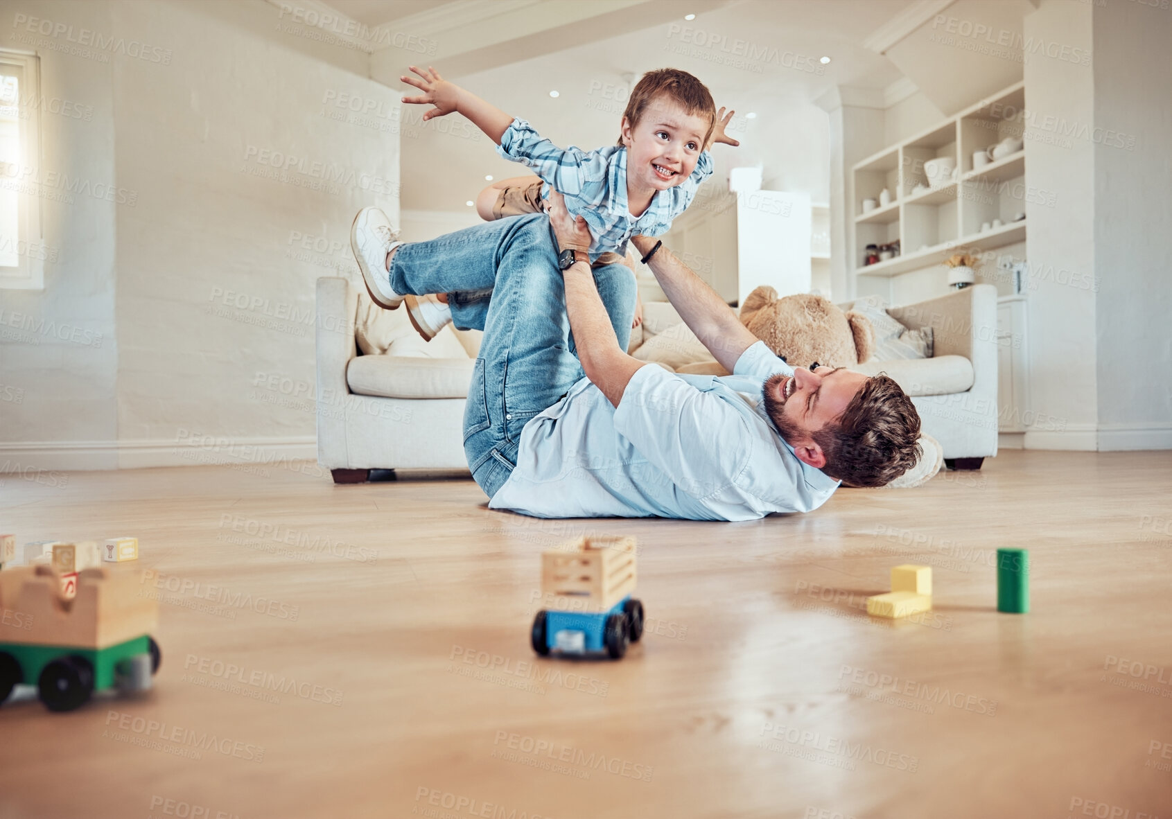 Buy stock photo Father lifting his son. Dad lying on the floor lifting his child. Little boy flying in dads arms. Excited father playing with his kid. Father and son bonding in the lounge at home.