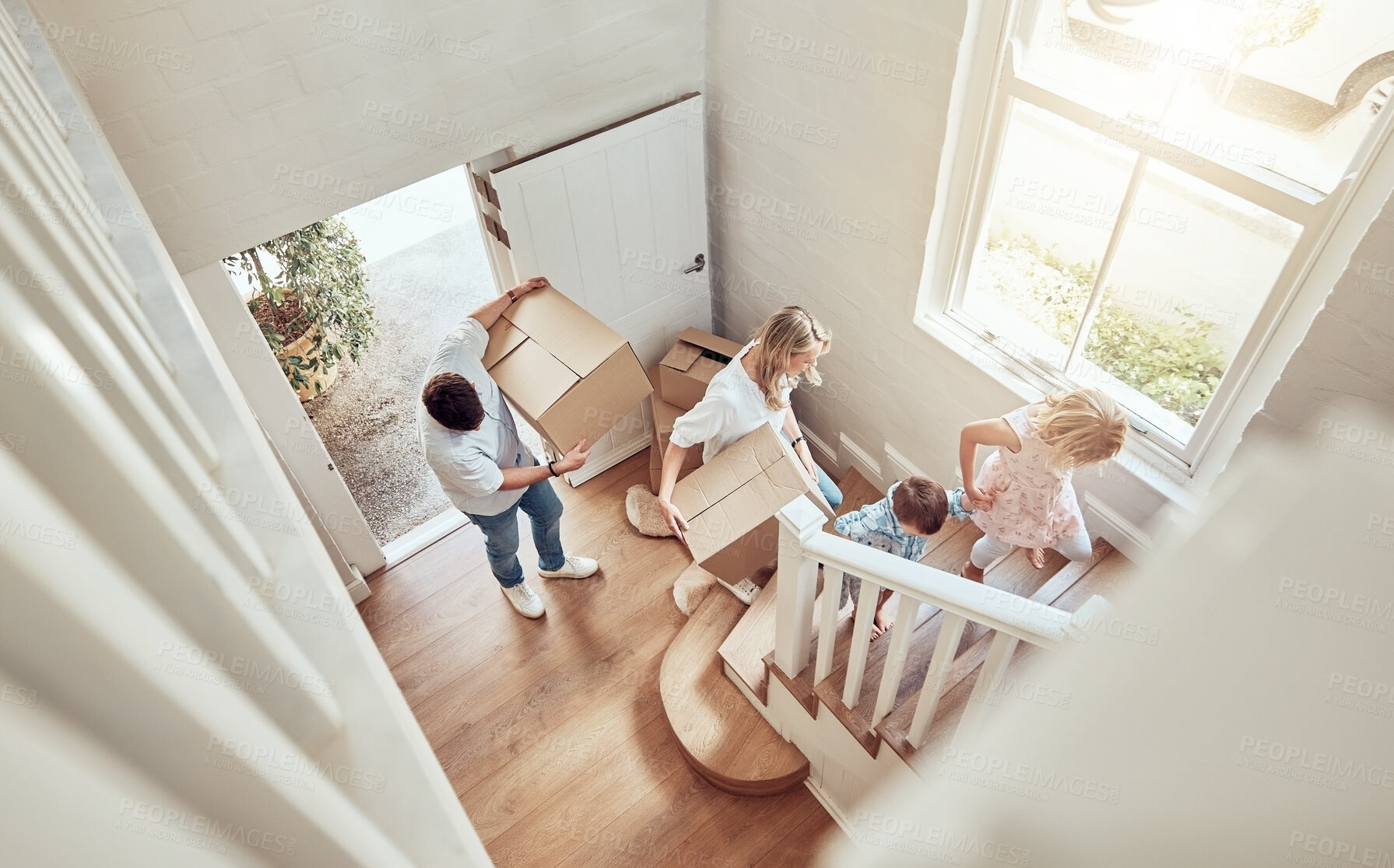 Buy stock photo Above view happy caucasian family moving into their new home and carrying boxes up a staircase. Parents and kids moving in. Mother, father, brother and sister taking their belongings into a new house