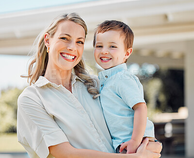 Portrait of happy caucasian mother holding cheerful son while having fun in the sun outside. Smiling woman carrying carefree boy while bonding in the yard. Loving mom enjoying quality time with kid
