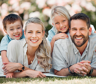 Happy caucasian family relaxing and lying on grass together in a park. Loving parents spending time with their son and daughter in nature. Joyful carefree siblings hugging their mom and dad outside