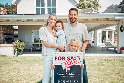 Portrait of happy caucasian family holding for sale and sold sign while relocating and moving in new house. Smiling parents and kids securing homeowner loan for property real estate and home purchase