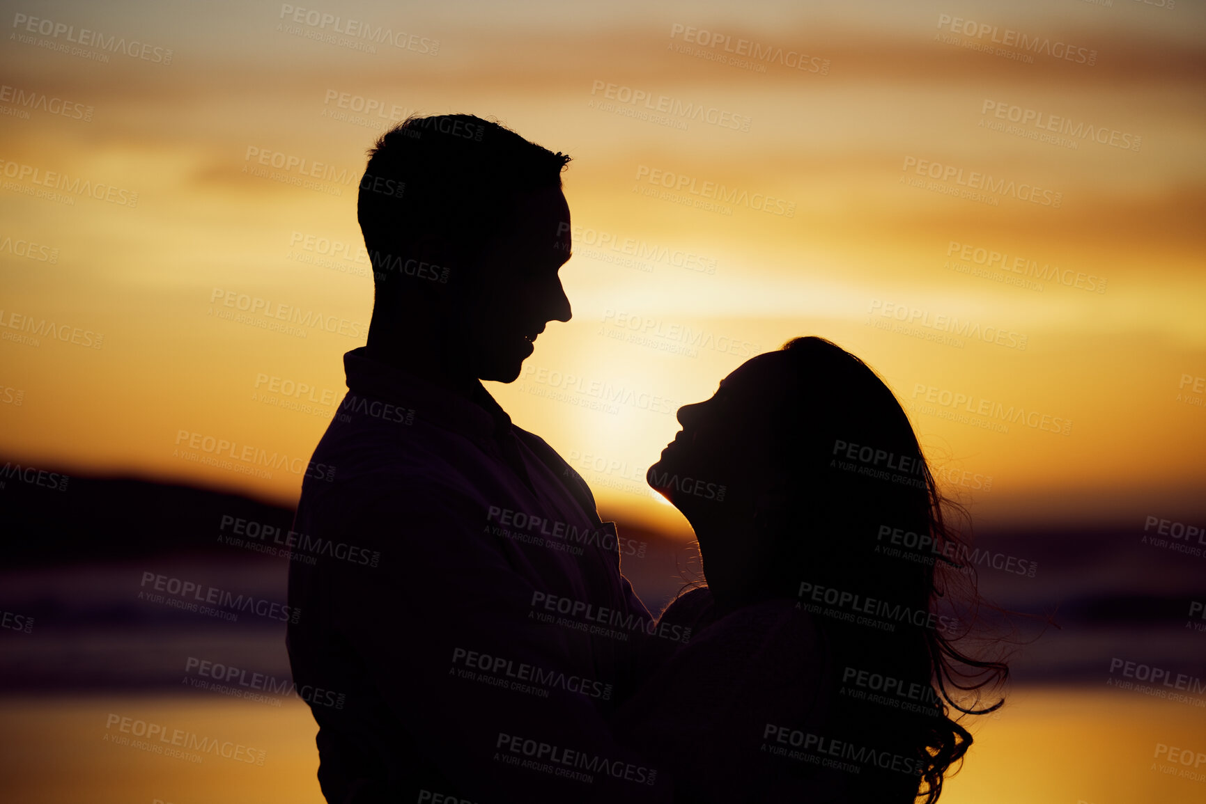 Buy stock photo Silhouette couple enjoying romantic moment standing face to face looking into eyes at sunset. Unknown boyfriend and girlfriend feeling in love while bonding at the beach