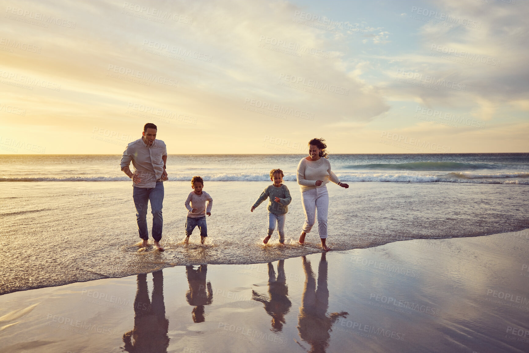 Buy stock photo Beach, sunset and parents play with children on holiday, summer vacation and weekend together. Travel, family and happy mother, father and kids run in ocean for bonding, adventure and quality time